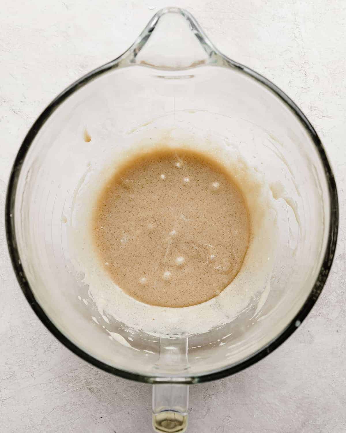 A tan liquid mixture in a glass stand mixer bowl.