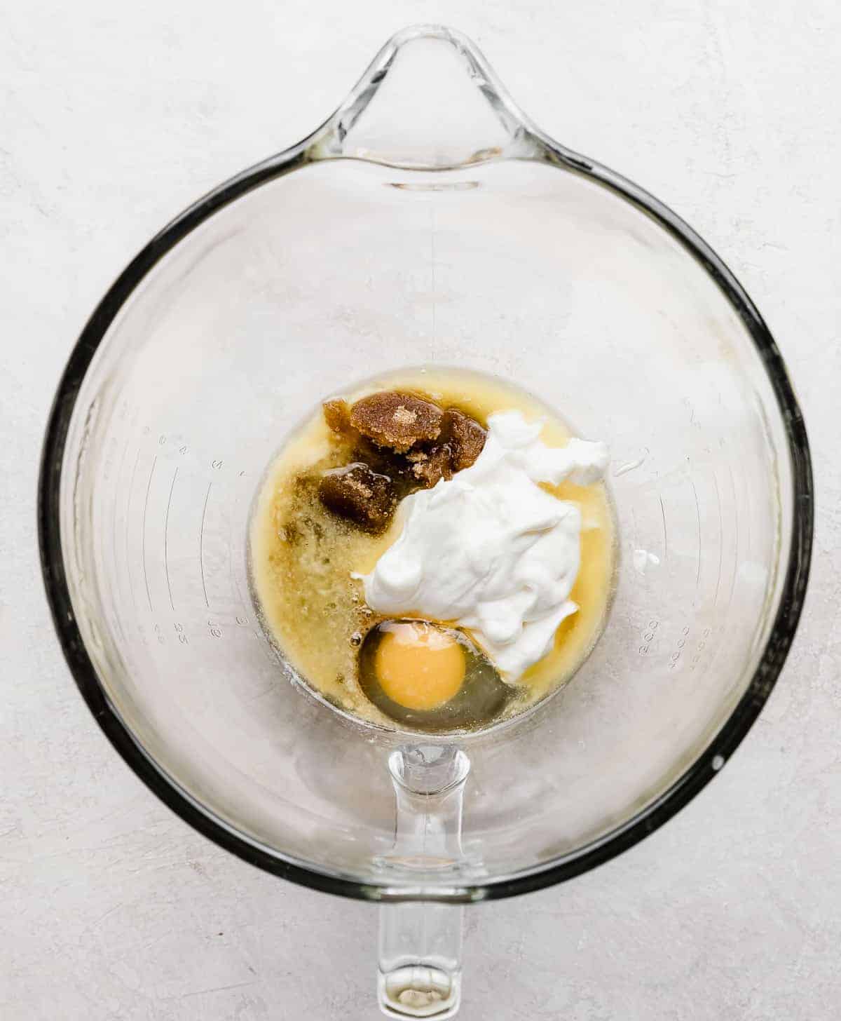 A glass bowl with sour cream, egg, and vanilla in it.