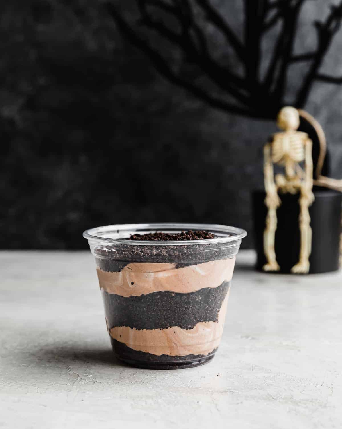 Halloween Dirt Cups featuring alternating layers of Oreo crumbs and chocolate pudding.