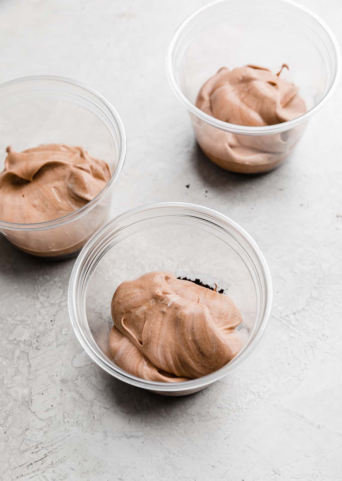 Clear plastic cups with crushed Oreos on the bottom and a layer of chocolate pudding on top.