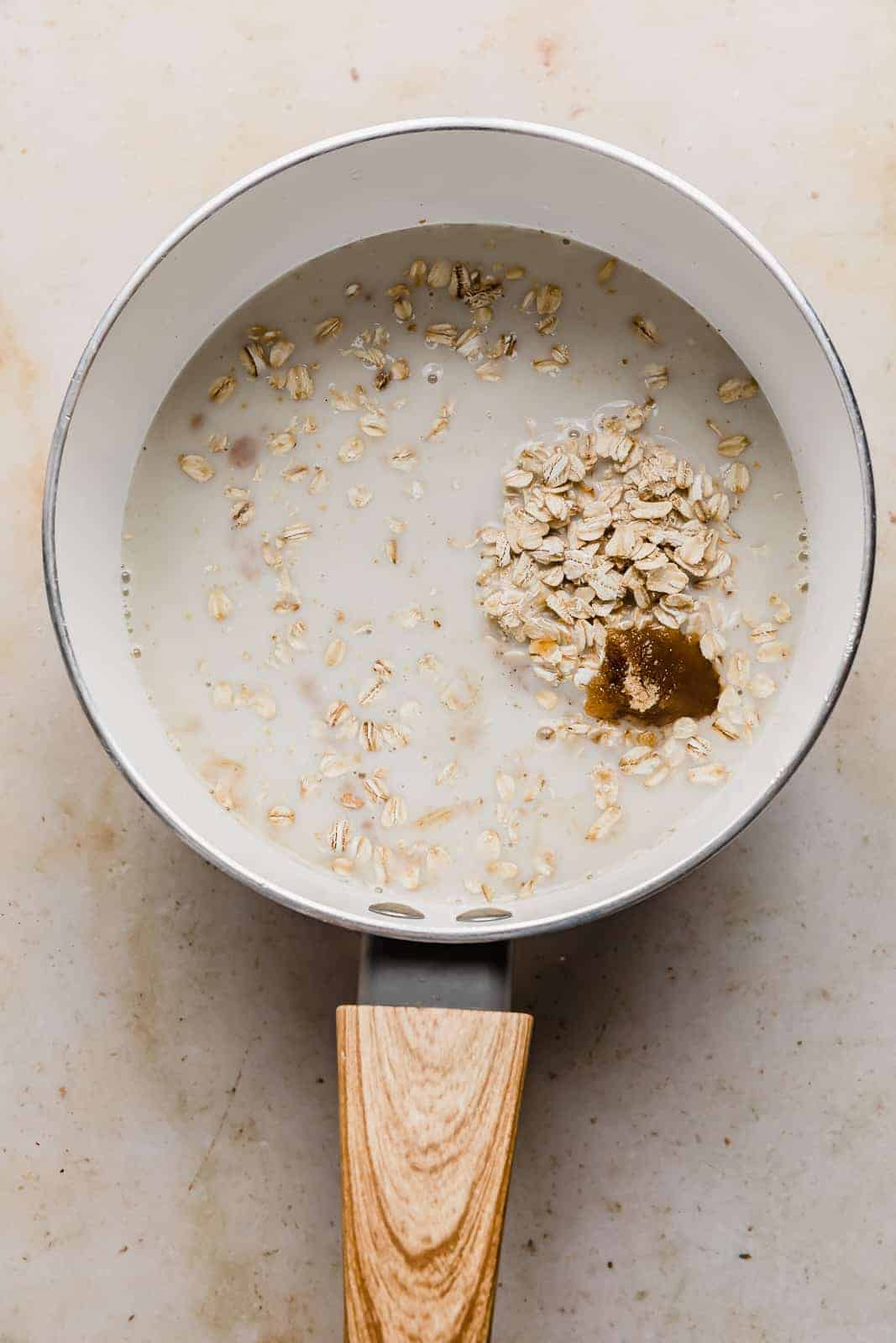 A white pot with milk, oats, brown sugar, and vanilla in it.