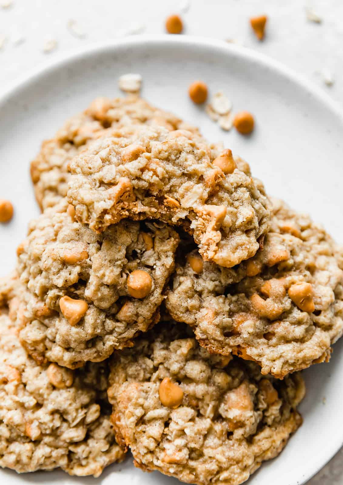 An Oatmeal Butterscotch Cookie with a bite taken out of it, on a white plate.