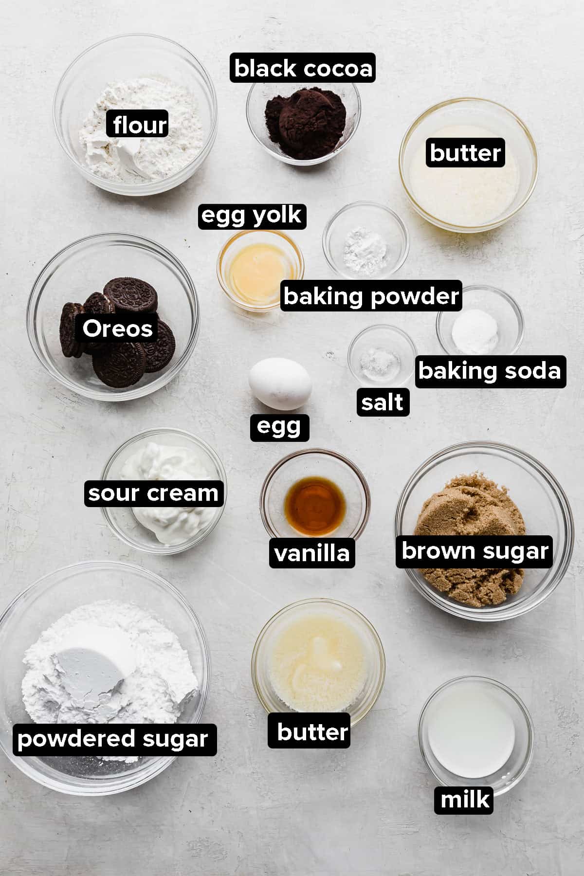 Oreo Donut ingredients in glass bowls on a gray background.