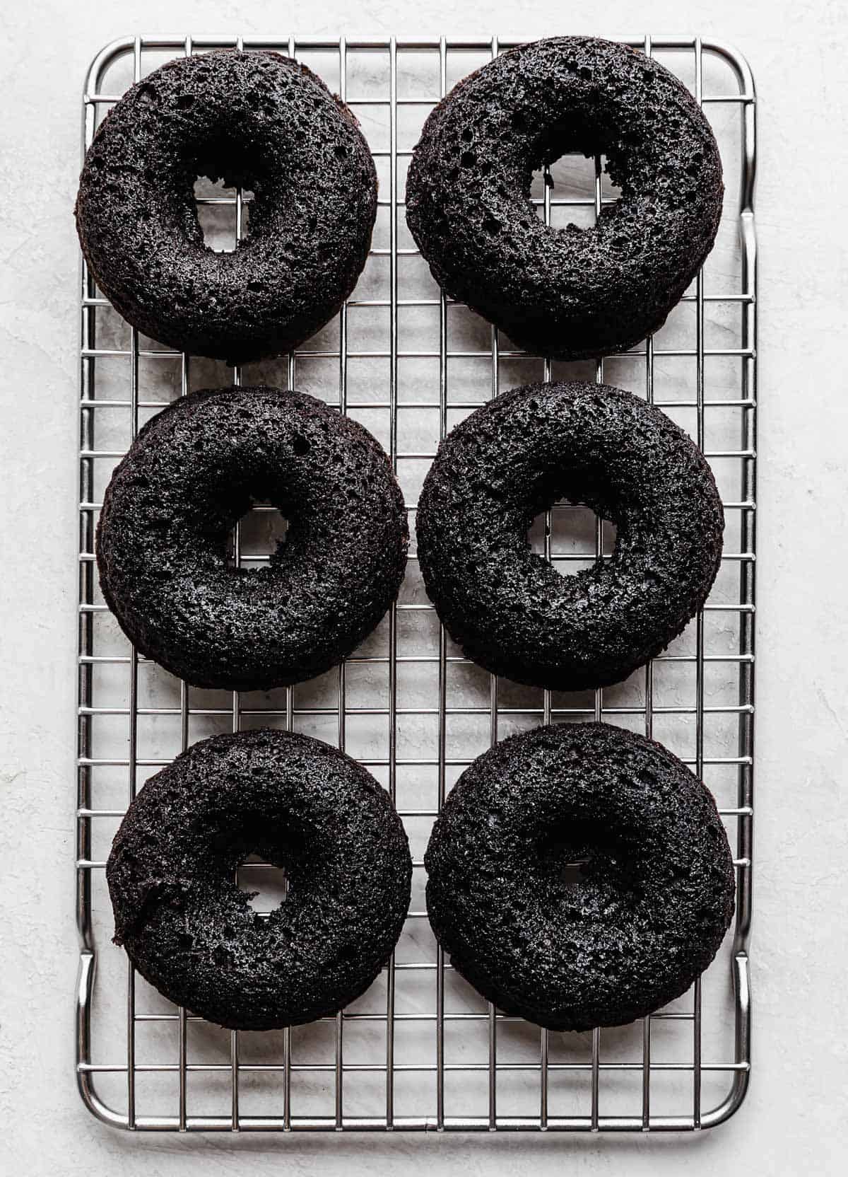 Six baked Oreo Donuts on a wire cooling rack.