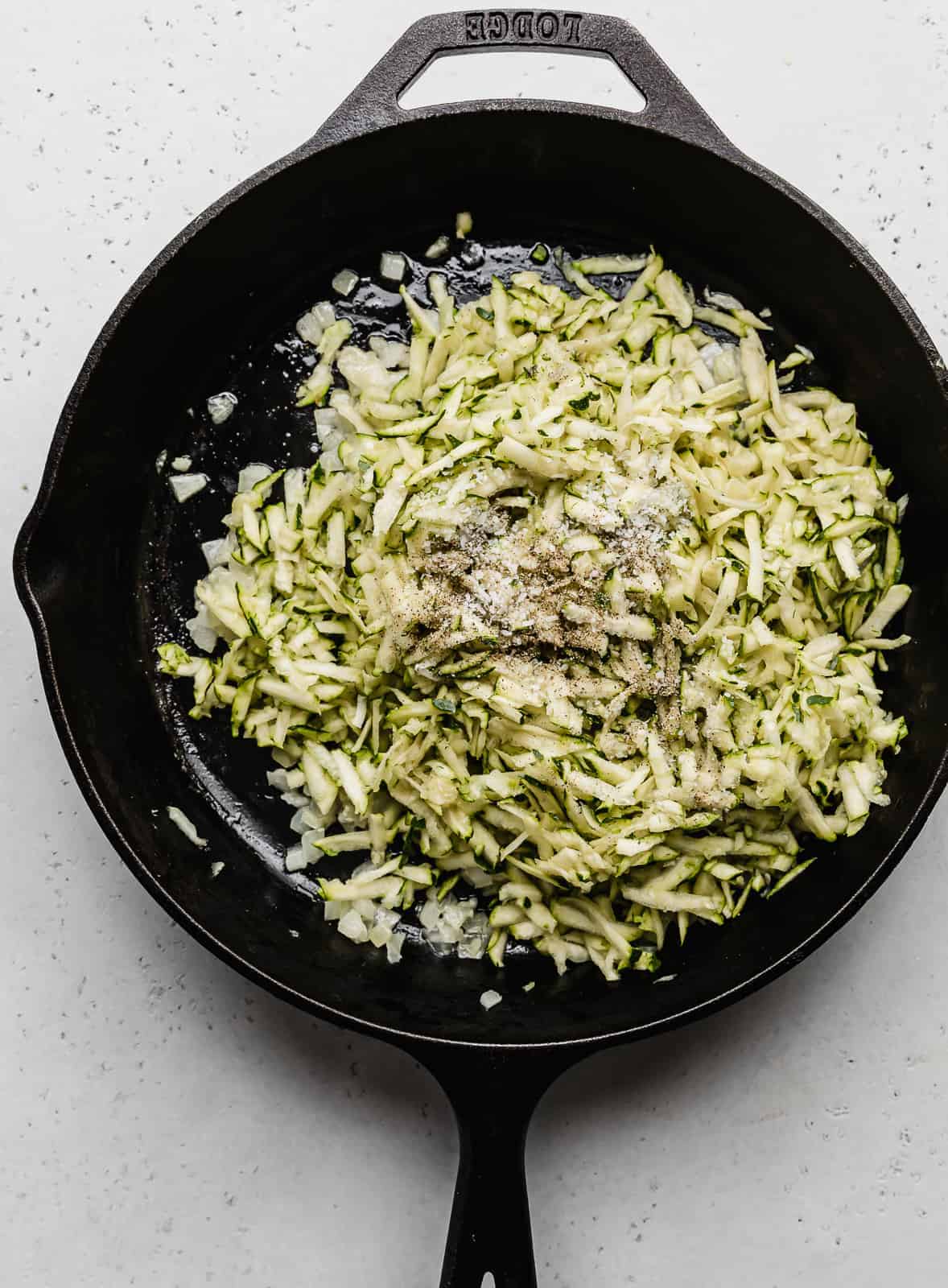 A black skillet with shredded zucchini in it.