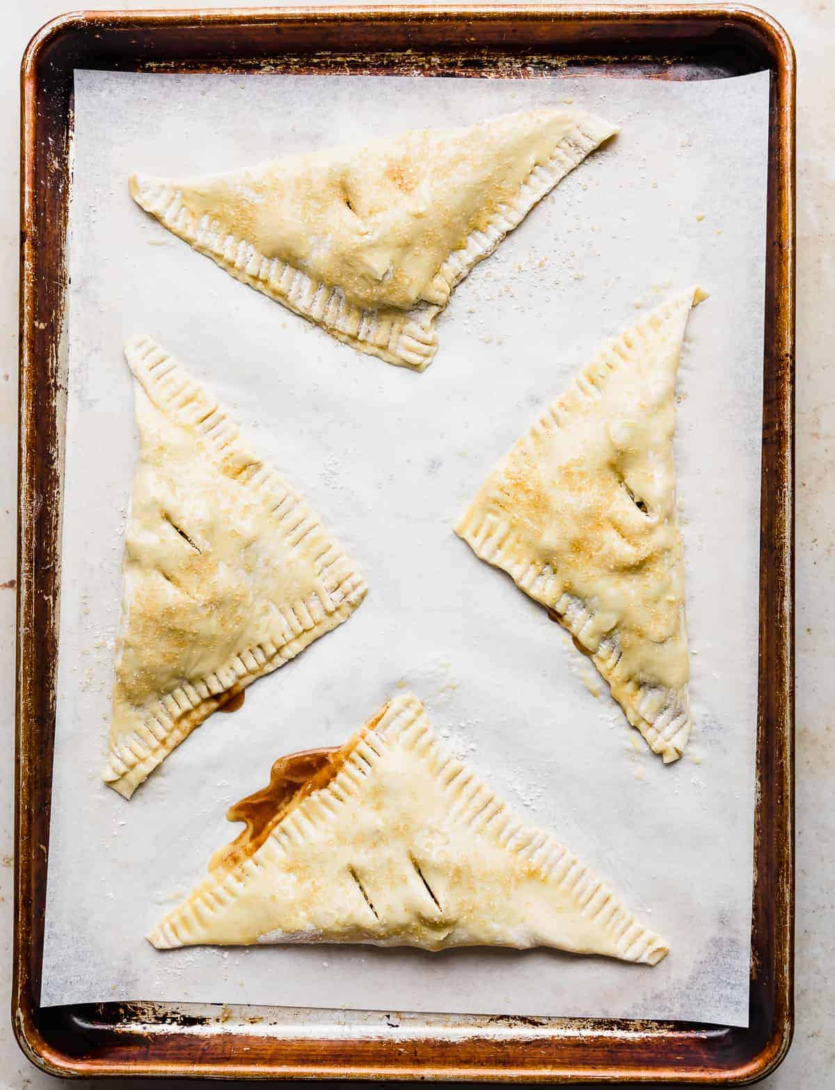 Unbaked Puff Pastry Apple Turnovers on a parchment lined baking sheet.