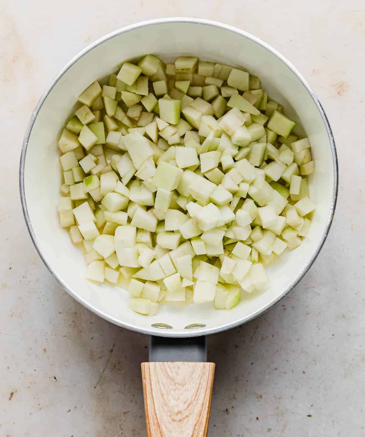 Diced apples in a white saucepan.