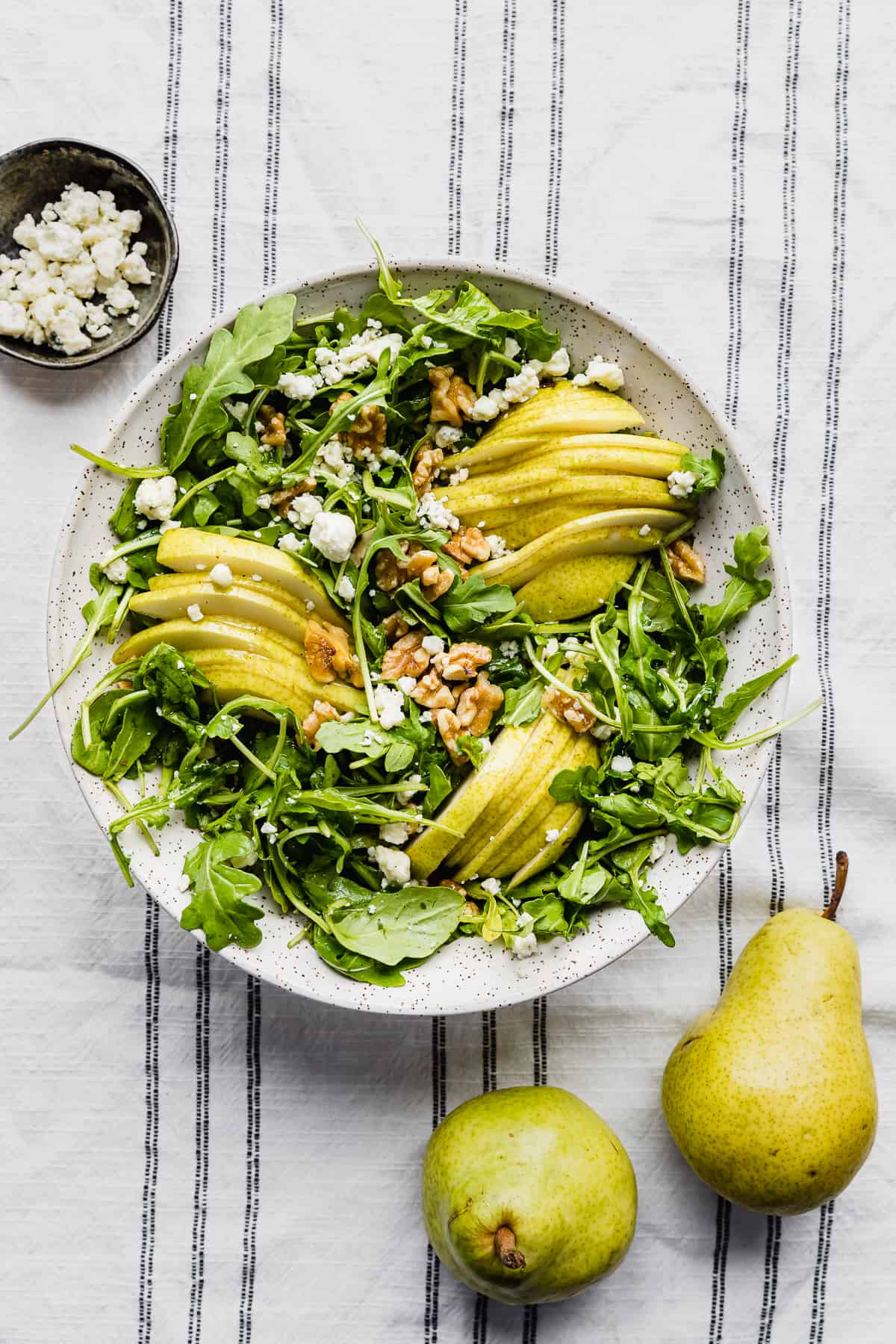 Rocket and Pear Salad on a white and black striped tablecloth.