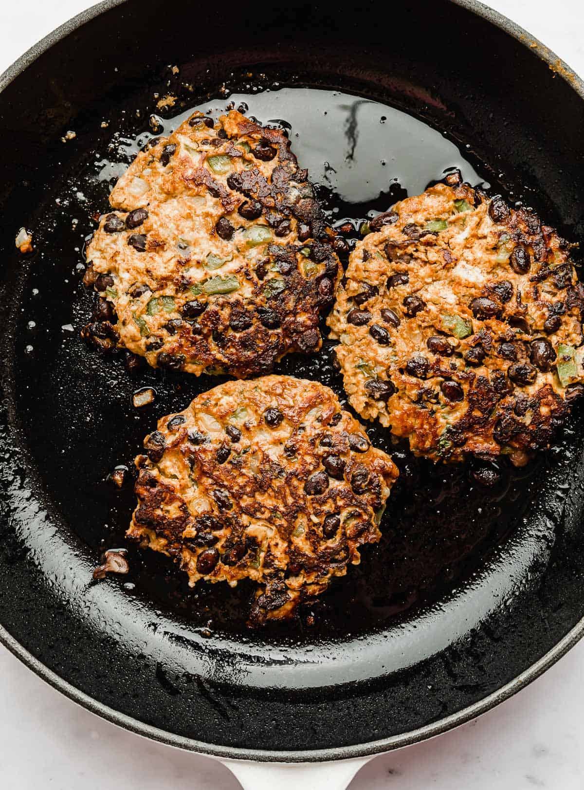 Cooked Taco Turkey Burger patties in a black skillet.
