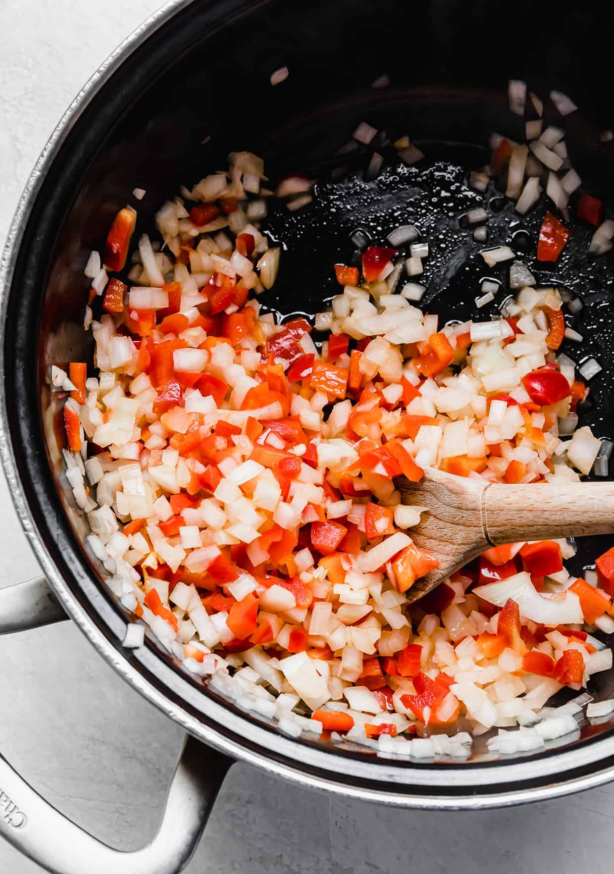 A black pot with diced onion and red pepper in it.