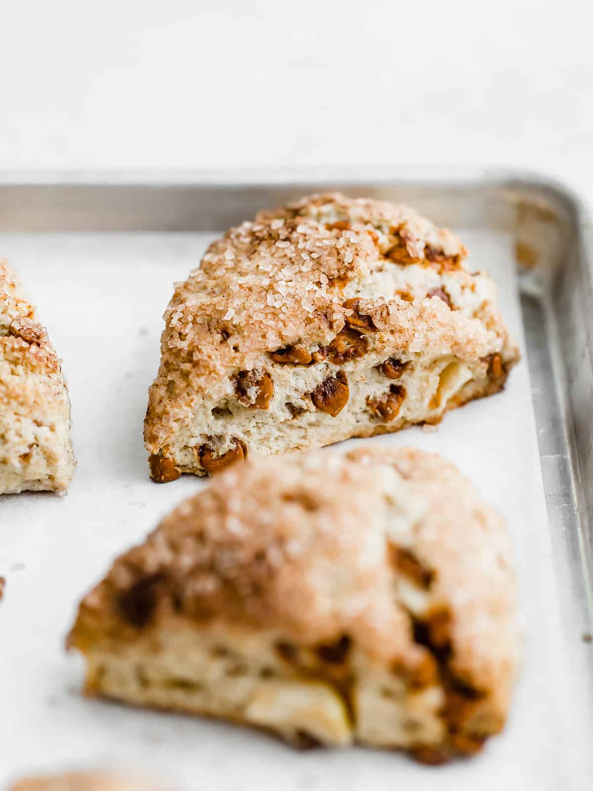 An apple cinnamon scone on a parchment lined baking sheet.