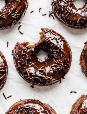 Chocolate Doughnuts on a white background with a bite taken out of it.