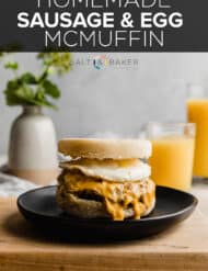 Homemade Sausage and Egg McMuffin on a black plate and wooden board.