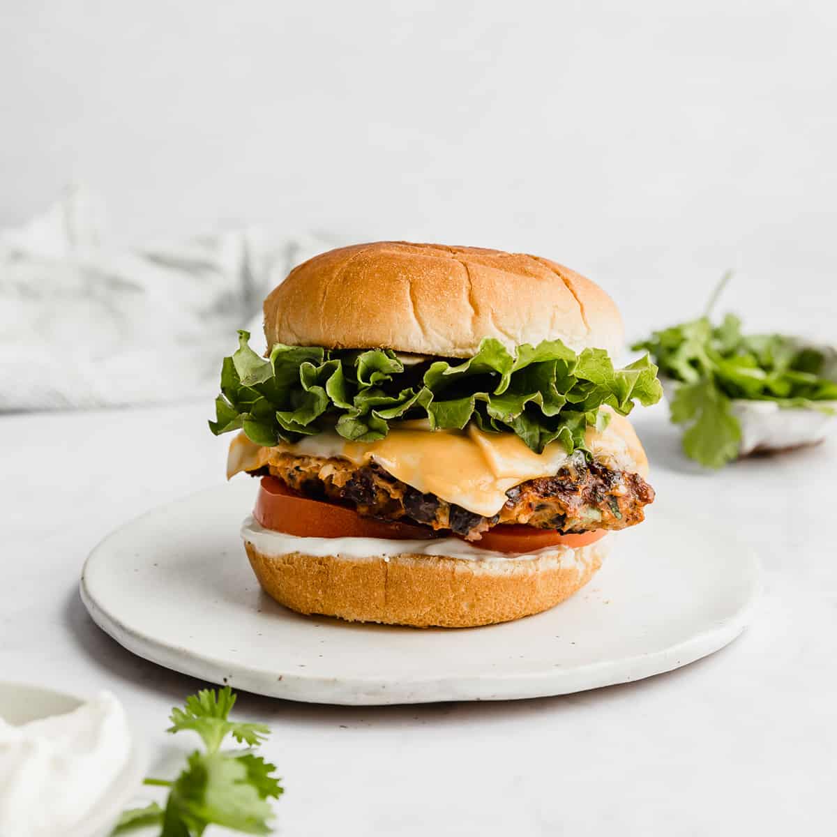 A Taco Turkey Burger on a bun with lettuce and tomatoes and orange cheese, against a white background.