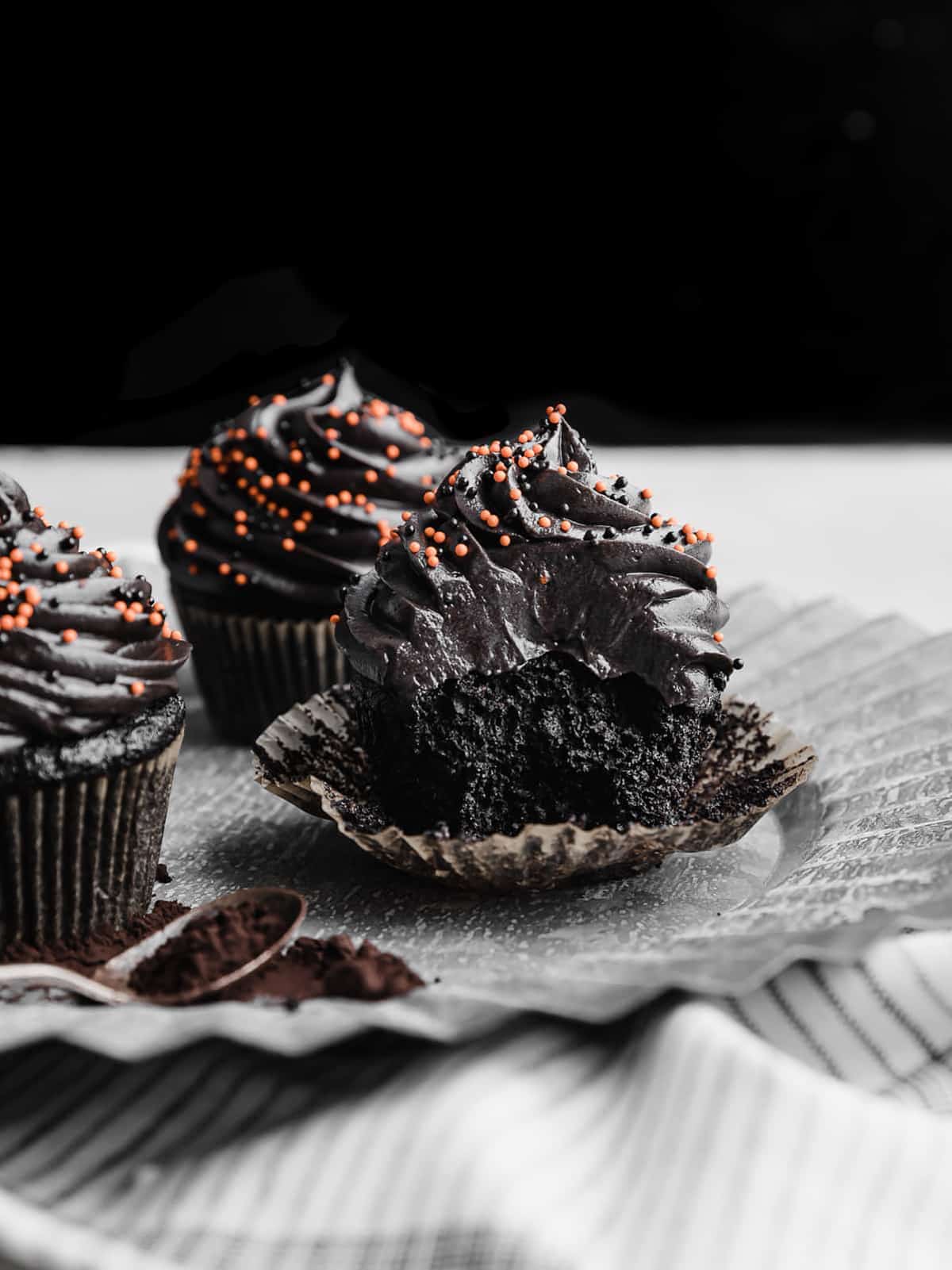 A Black Velvet Cupcake on a gray metal plate with a bite taken out of the cupcake.