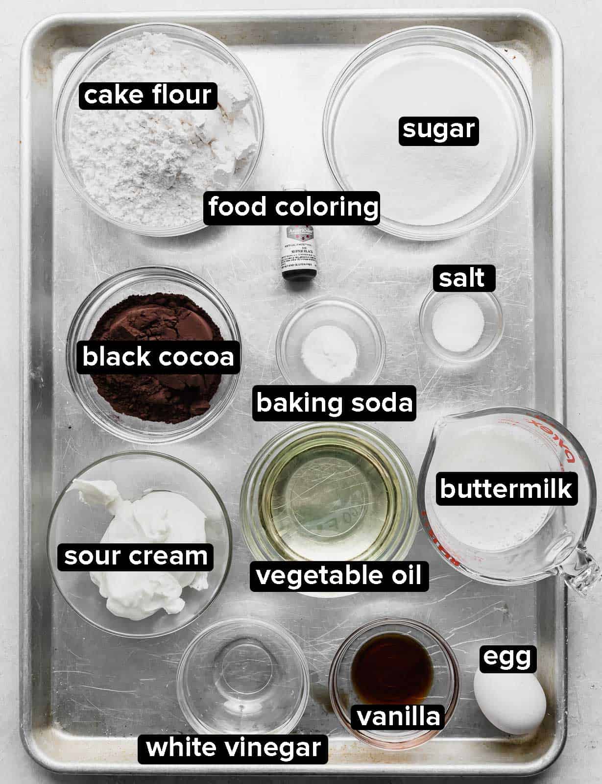 Ingredients used to make Black Velvet Cupcakes on a baking sheet.