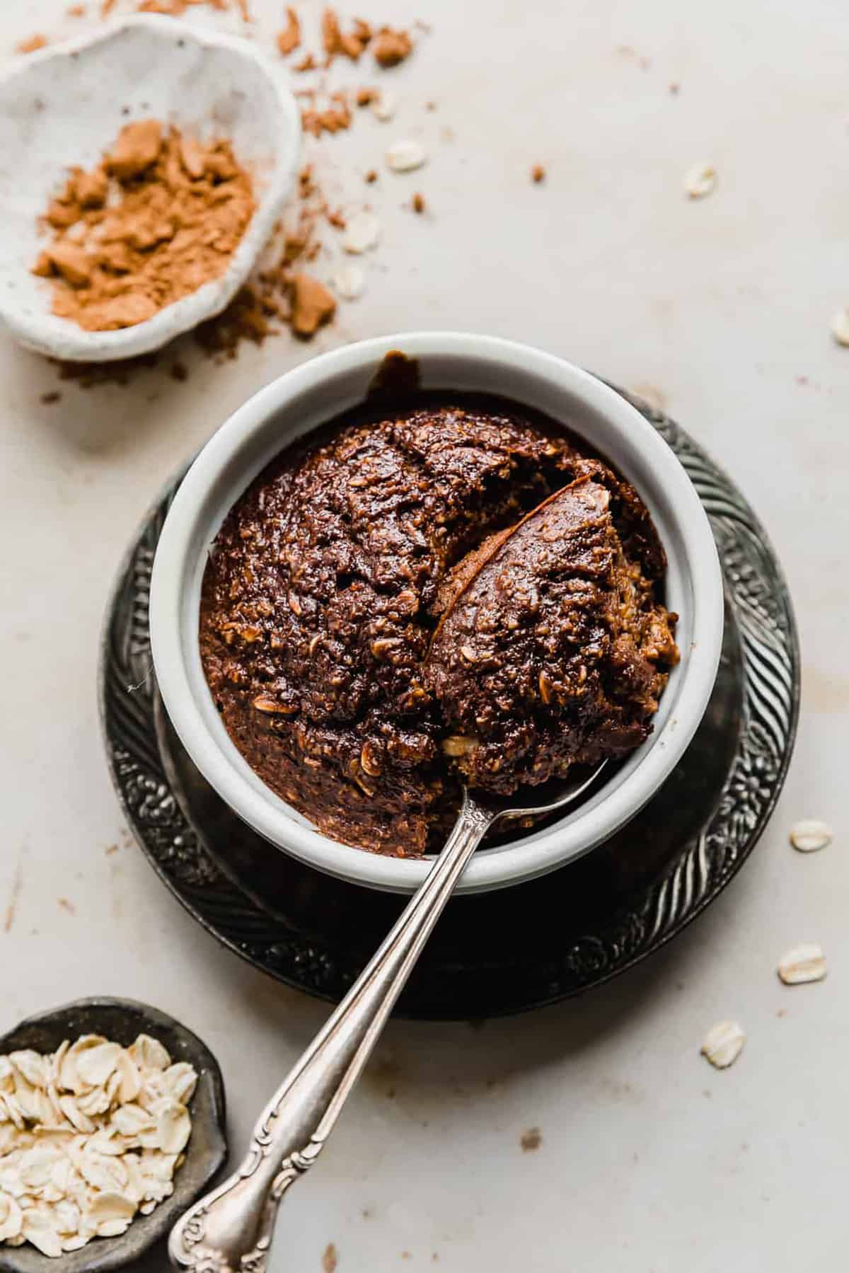Chocolate Baked Oats in a white ramekin with a spoon scooping out some oats.