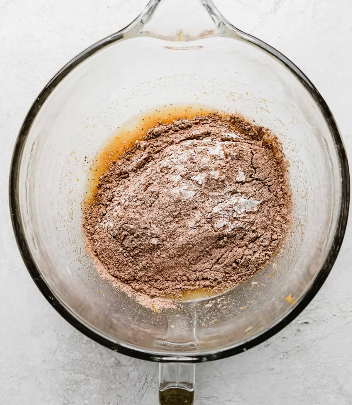 A light brown flour mixture in a glass stand mixer bowl on a gray background.