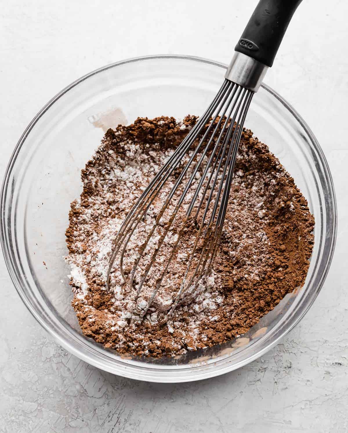 A whisk mixing a flour and cocoa powder for making chocolate orange cupcakes.