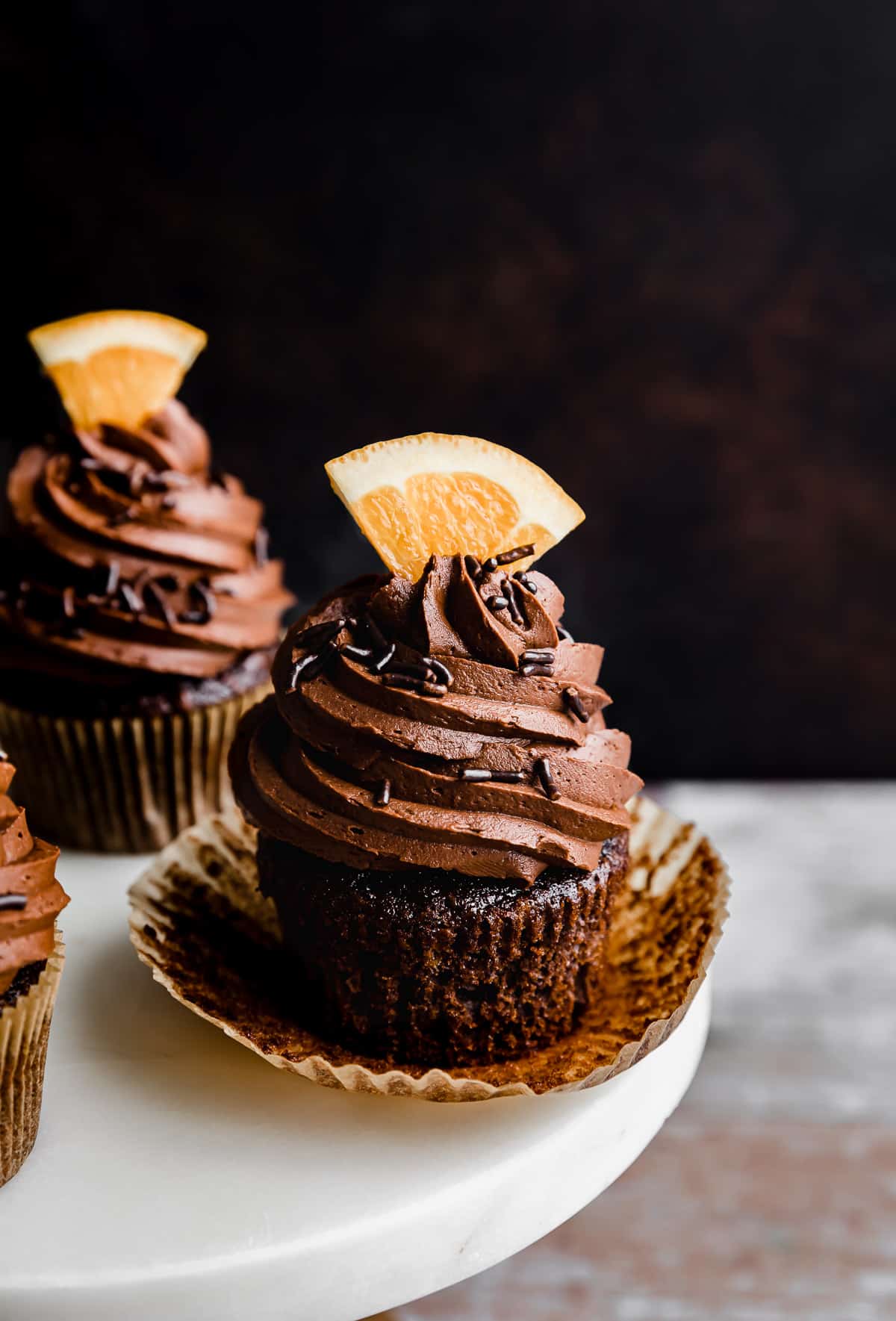 A Chocolate Orange Cupcake with a fresh orange slice on top of the frosting.