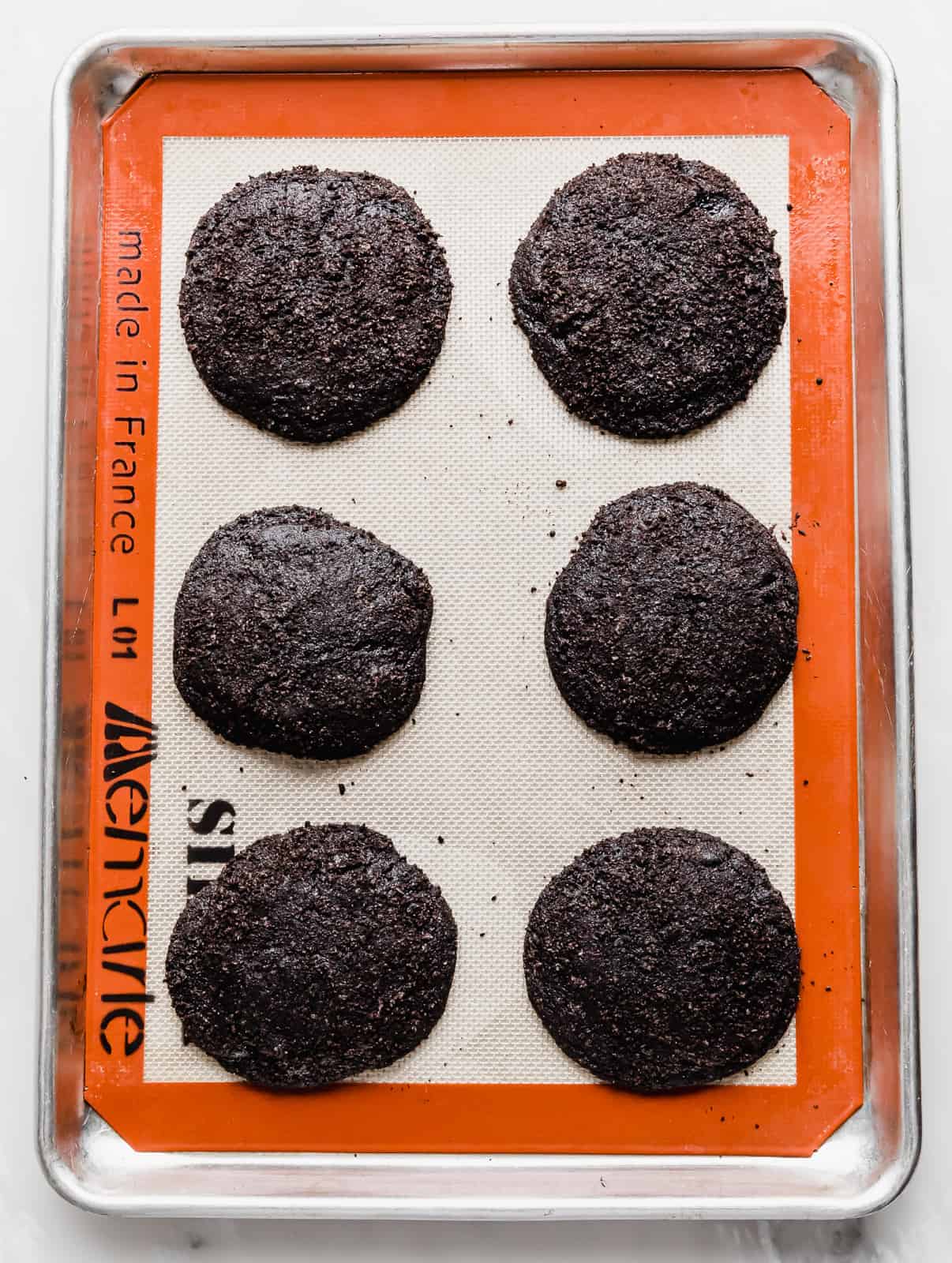 Six Crumbl Chocolate Oreo Cookies on a baking sheet.
