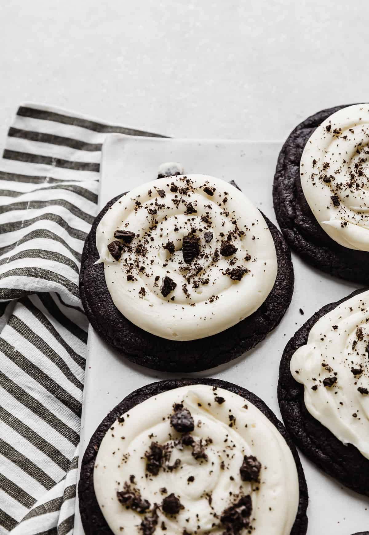 A black cookie topped with cream cheese frosting and crushed Oreos.