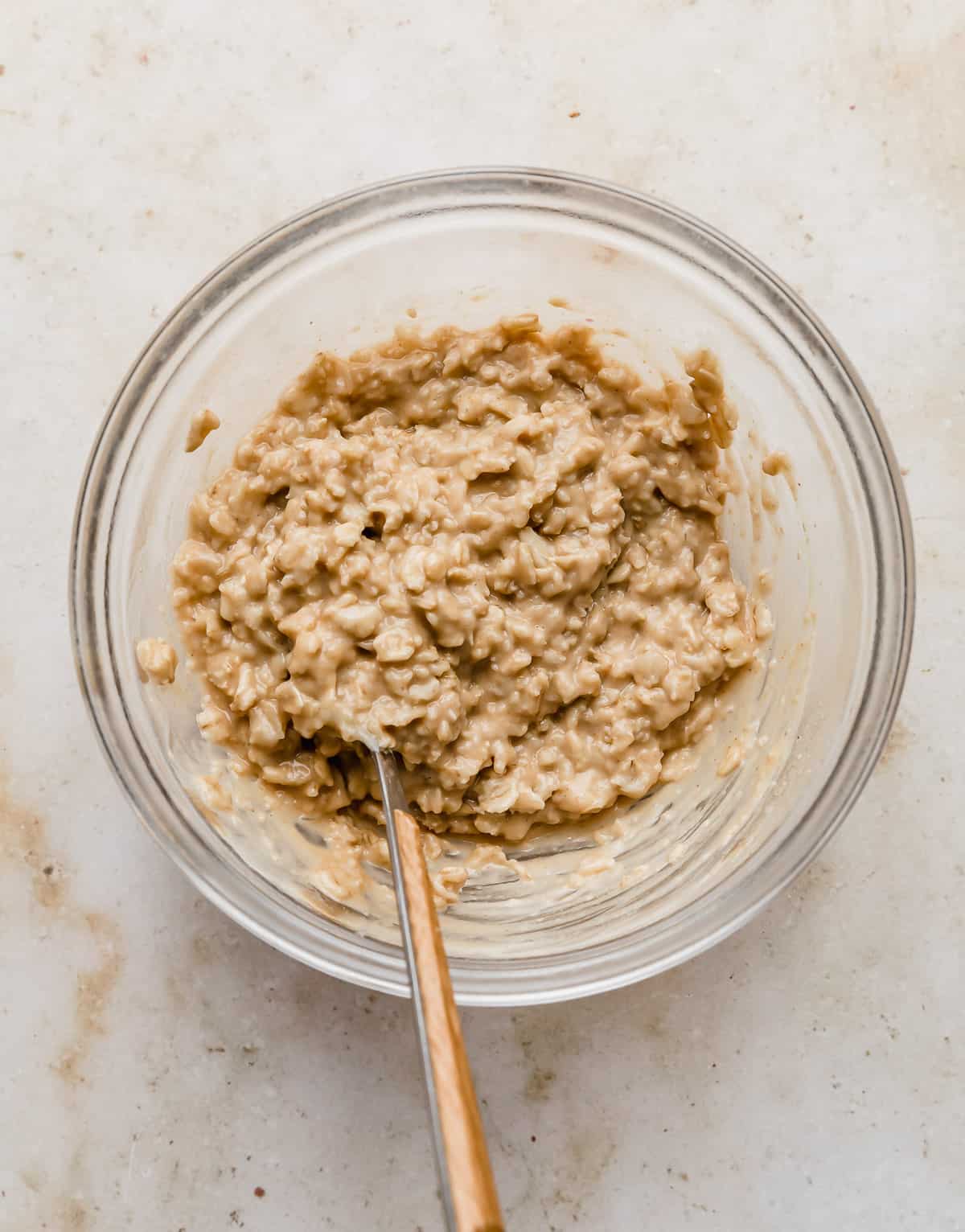 A glass bowl with tan colored peanut butter oatmeal in it.