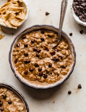 A black bowl full of Chocolate Peanut Butter Protein Oatmeal topped with mini chocolate chips.