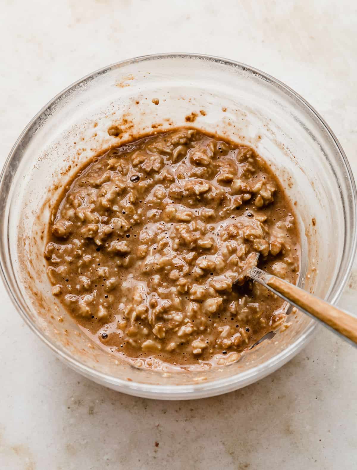 Chocolate Peanut Butter Protein Oatmeal in a glass bowl on a cream colored marble background.