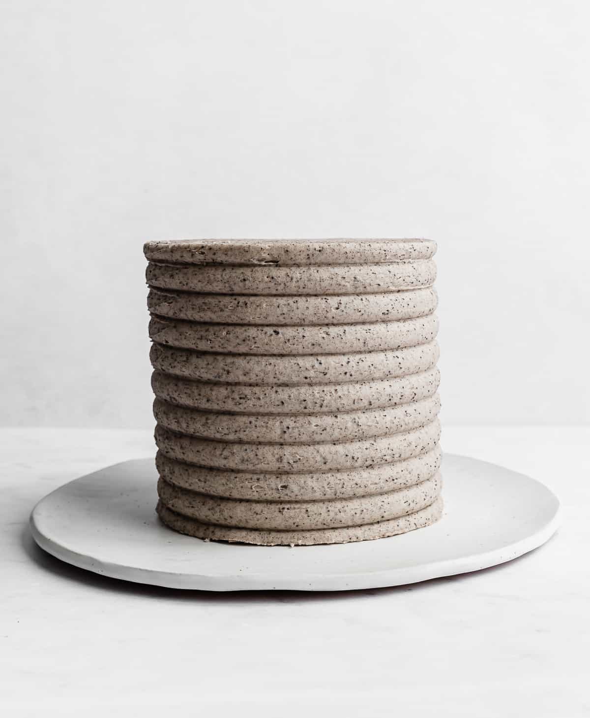 A cookies and cream frosting coated cake on a white background.
