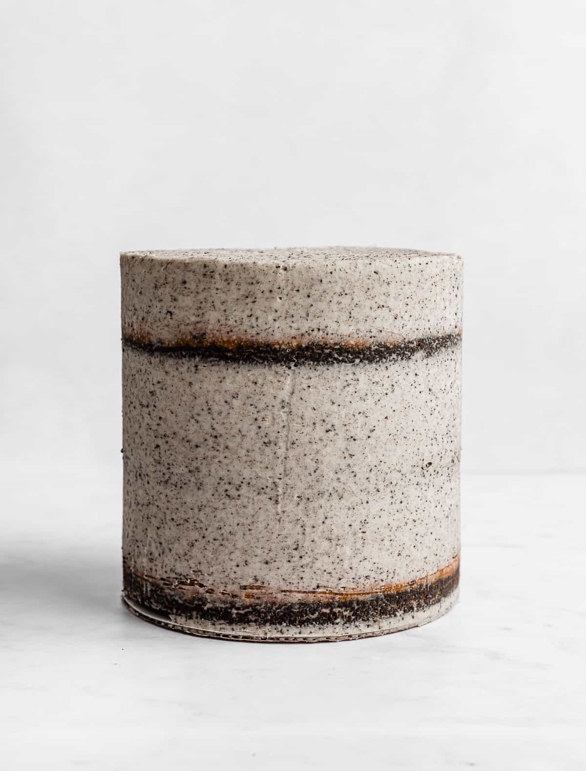A three tiered six inch cake covered in a cookies and cream crumb coat, on a white background.