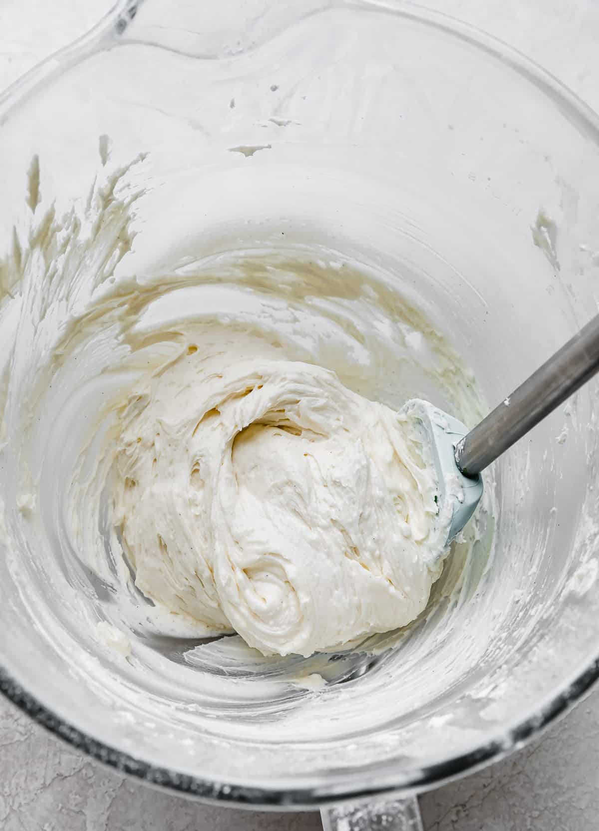 White frosting in a glass mixing bowl.