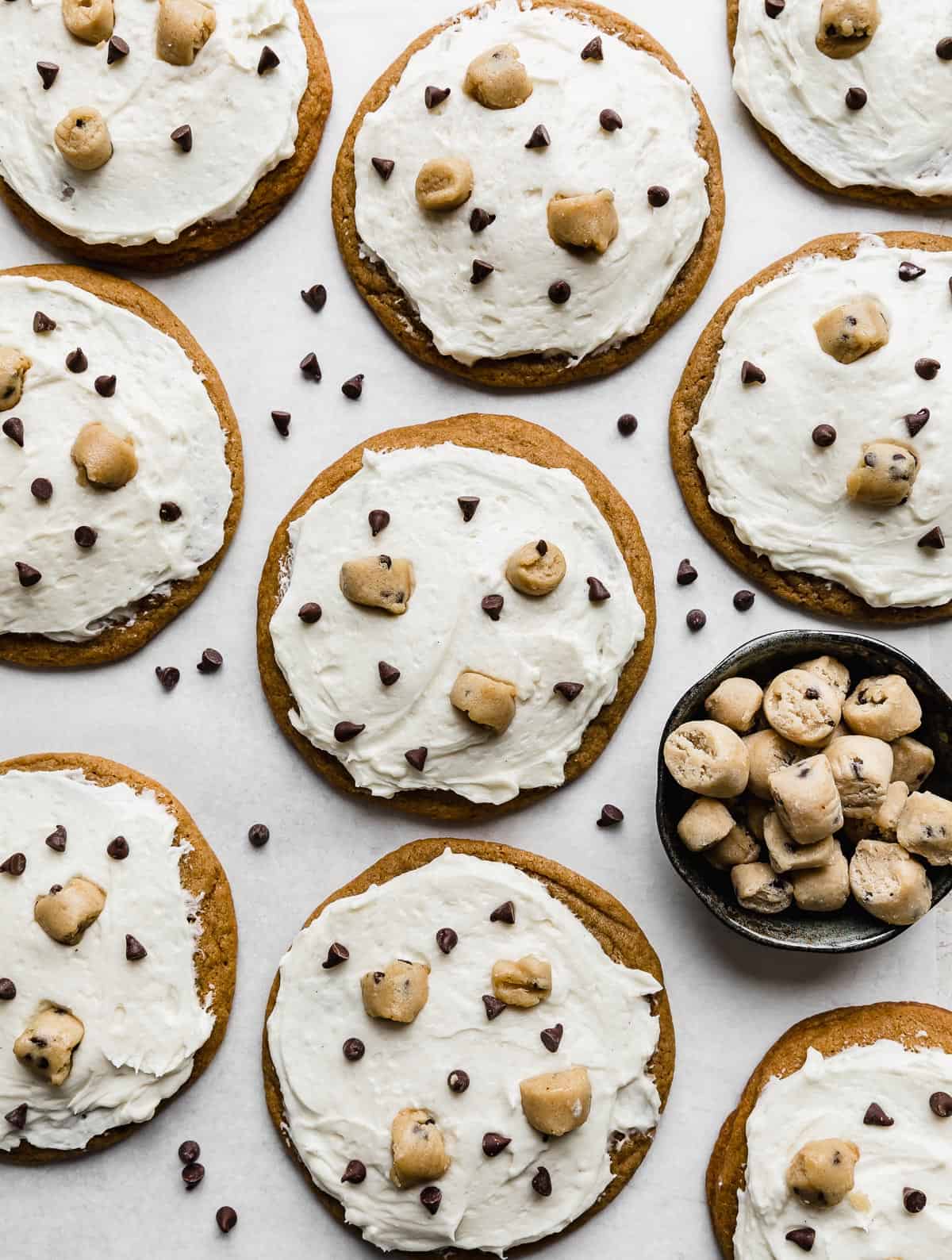 Brown sugar cookies topped with a white frosting, mini chocolate chips and cookie dough chunks.