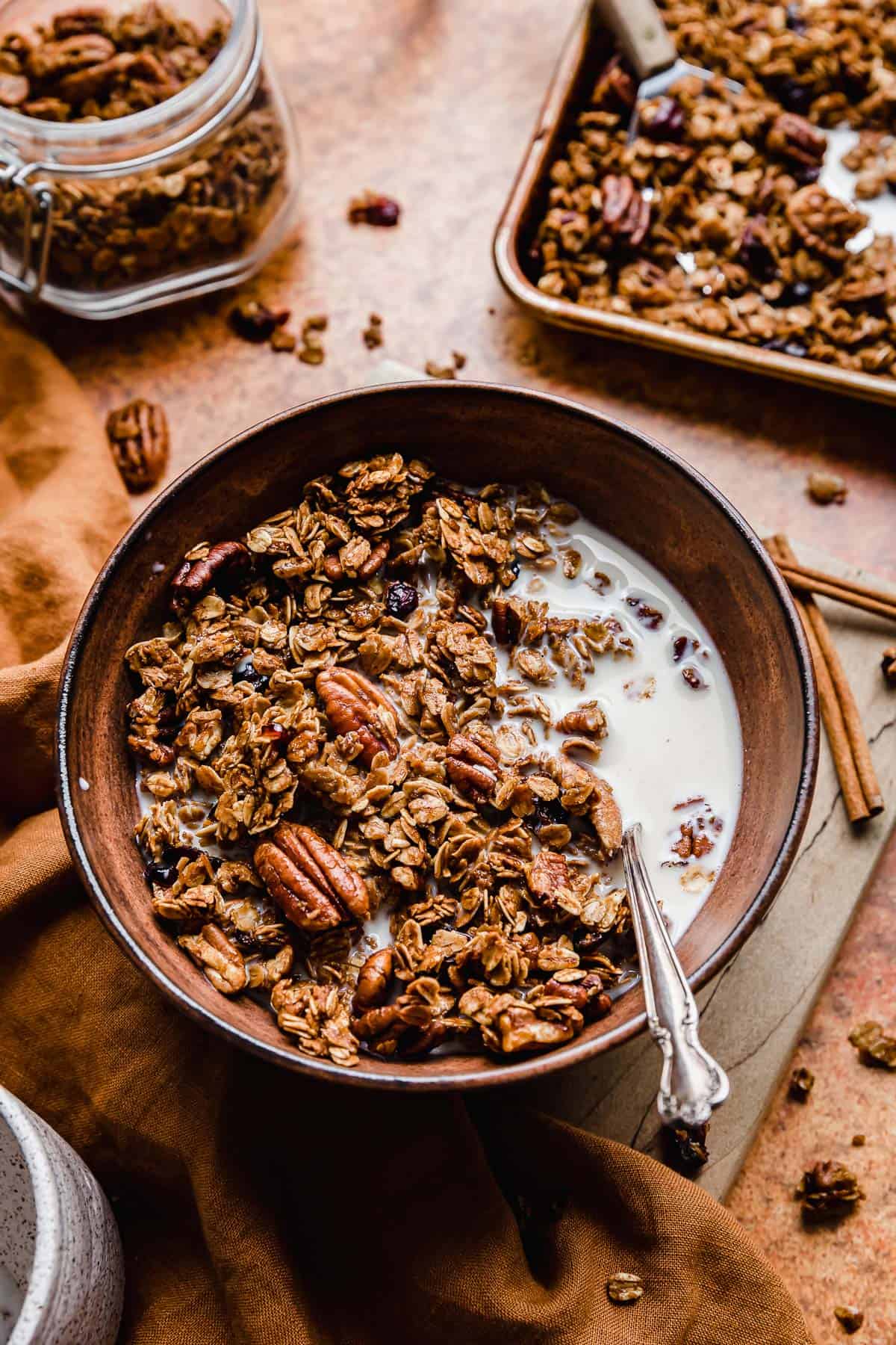 Gingerbread Granola in a brown bowl with milk and a spoon.