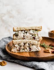 Leftover Turkey Salad on slices of bread that are cut in half, stacked on top of each other on a brown plate.
