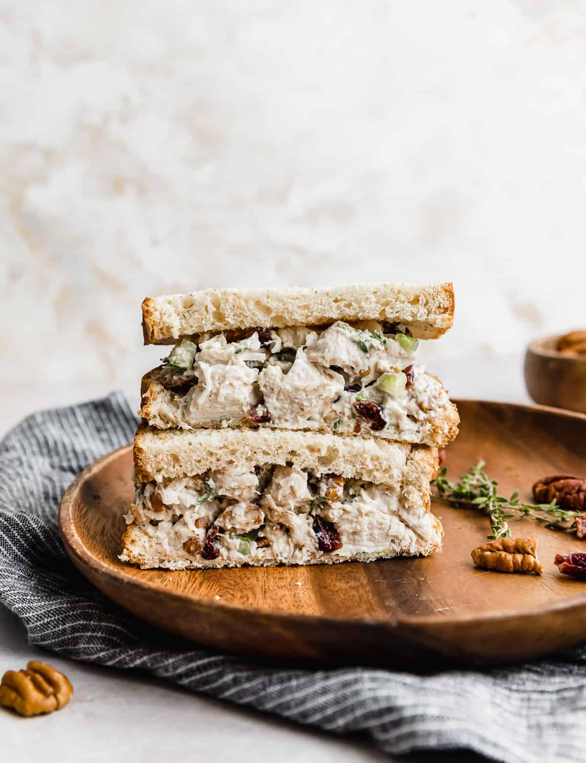 Leftover Turkey Salad on slices of bread that are cut in half, stacked on top of each other on a brown plate.