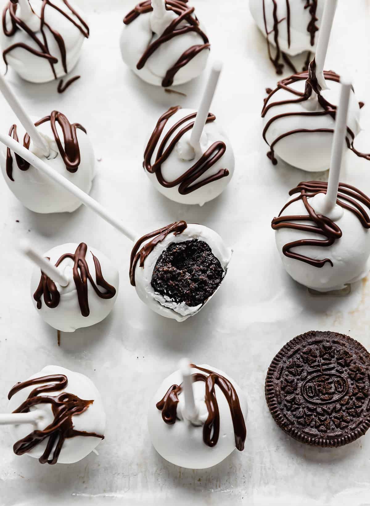 Oreo Cake Pops covered in white chocolate and drizzled with chocolate.