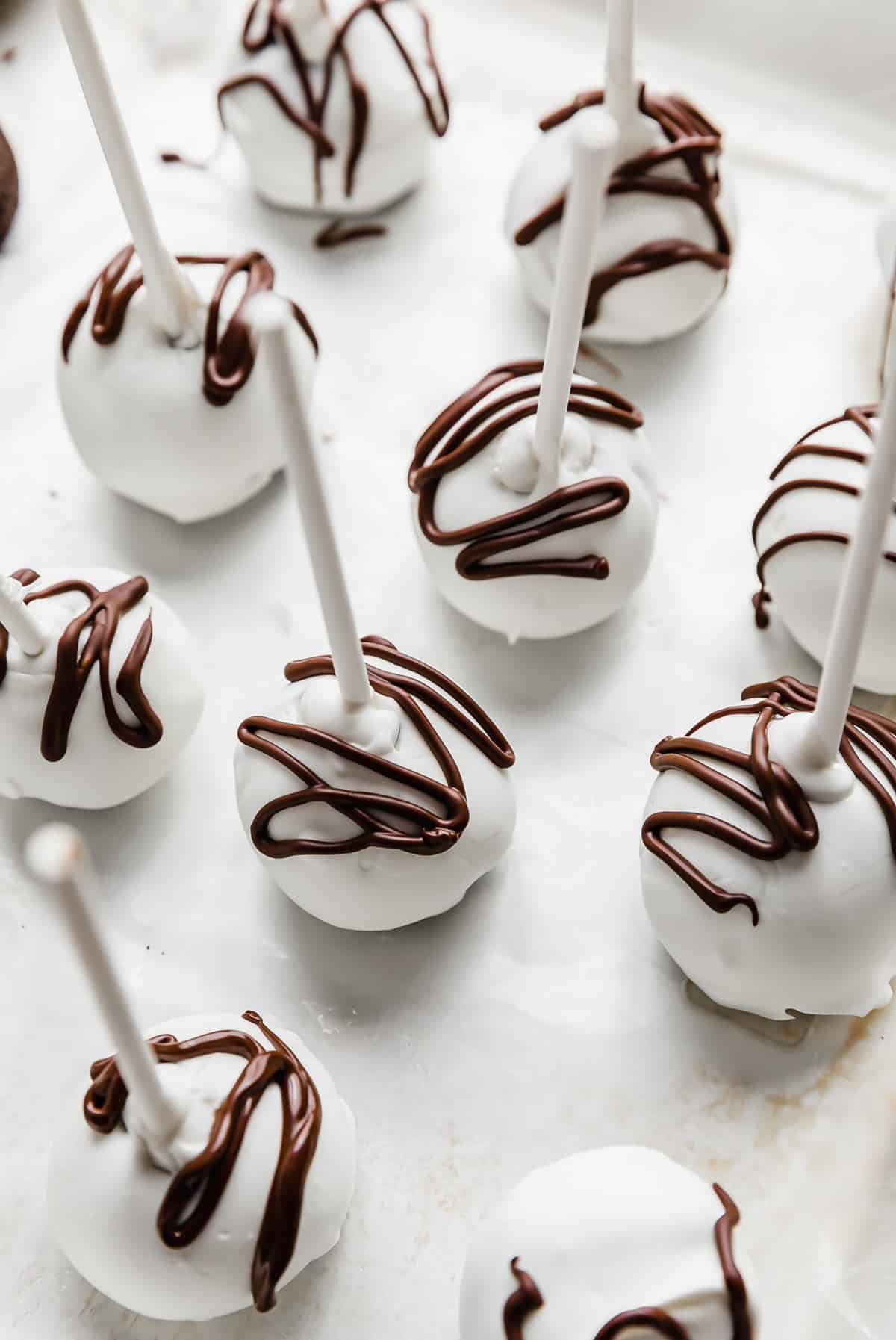 Oreo Cake Pops covered in white chocolate and drizzled with brown chocolate overtop.