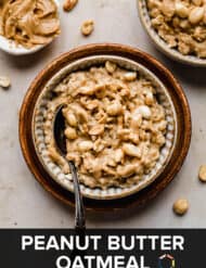 Peanut Butter Oatmeal in a brown bowl on a tan marble background with peanuts surrounding the bowl.