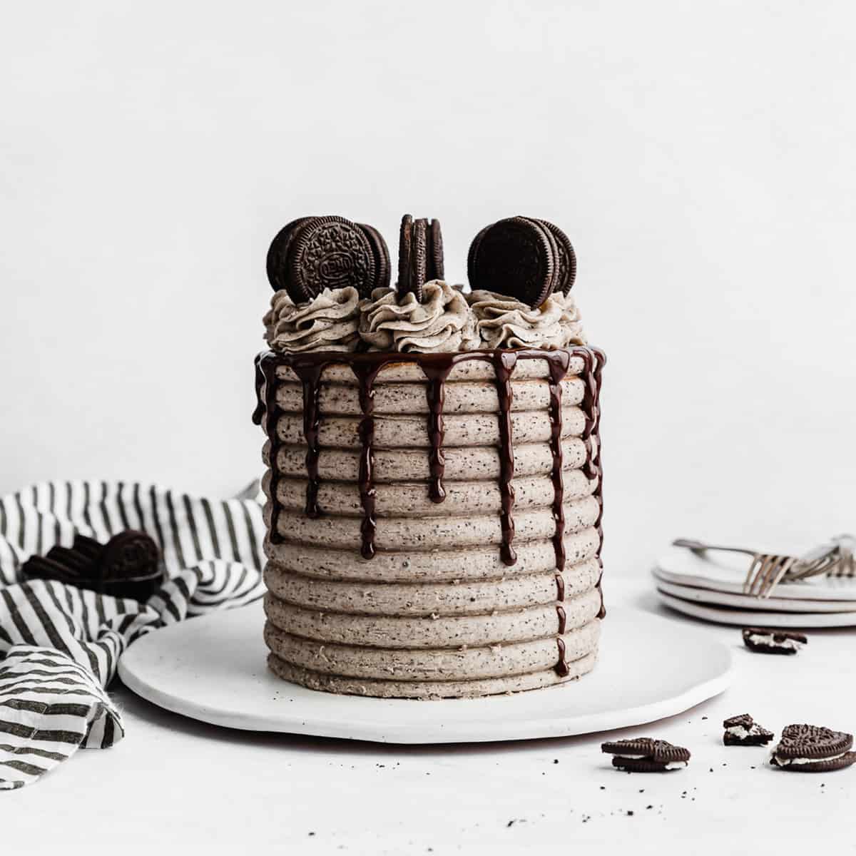 A Coconut Cookies and Cream Cake on a white plate against a white background.