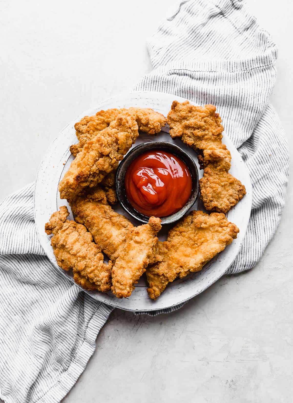 Air Fryer Frozen Chicken Tenders on a white plate on a white background.