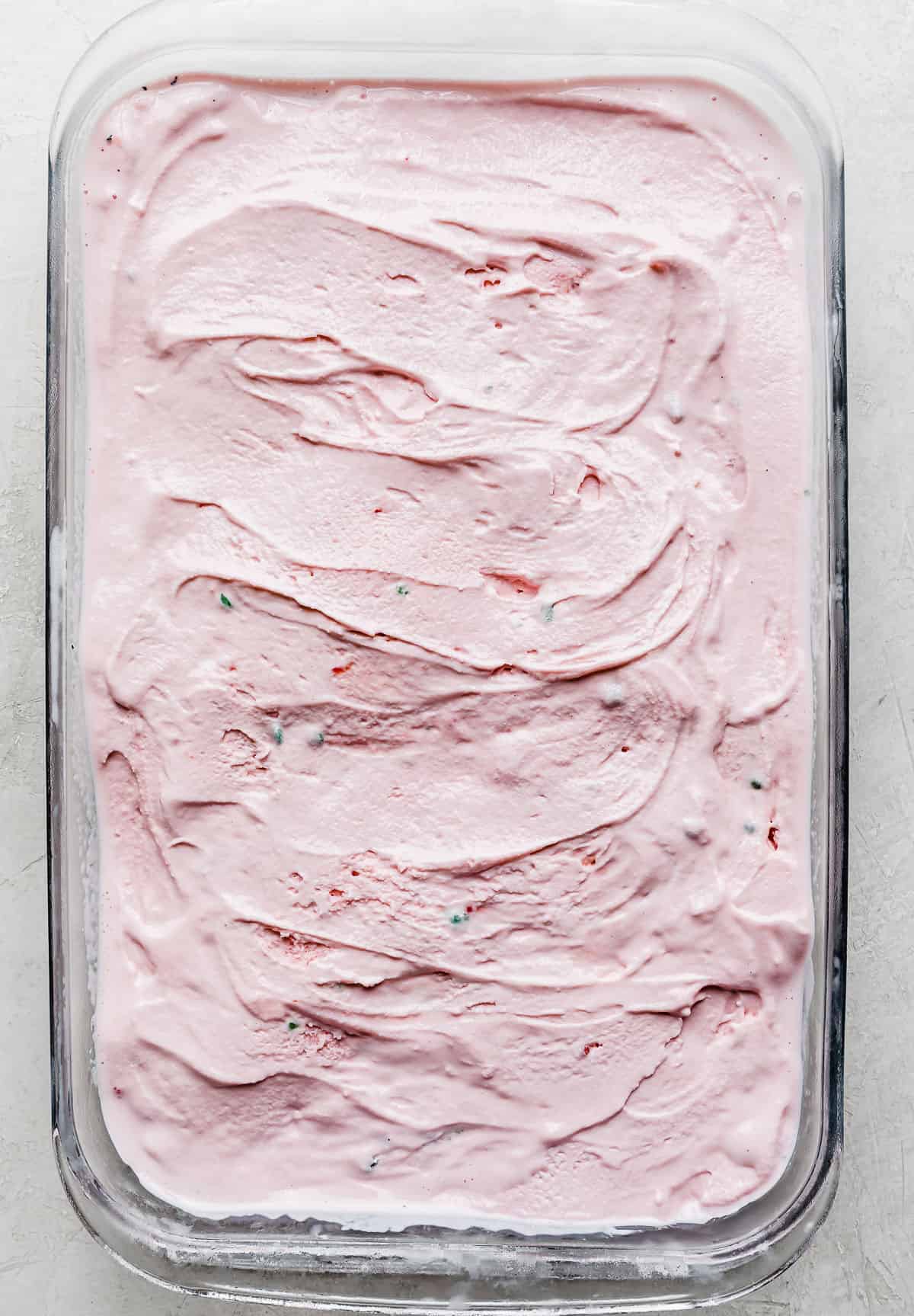 A glass dish with pink peppermint ice cream spread into an even layer.