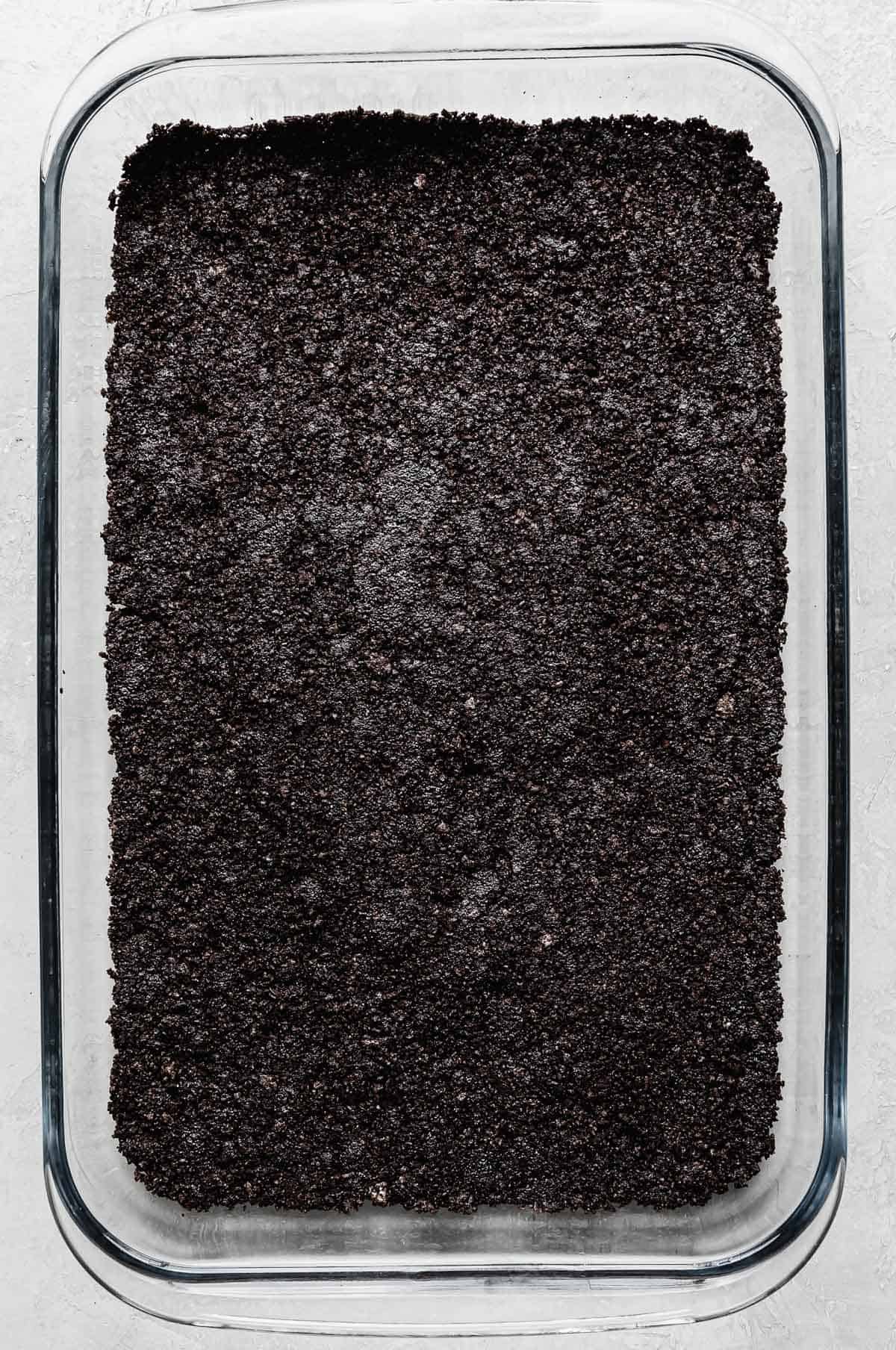 A rectangular glass dish with Oreo crust pressed along the bottom of the pan.