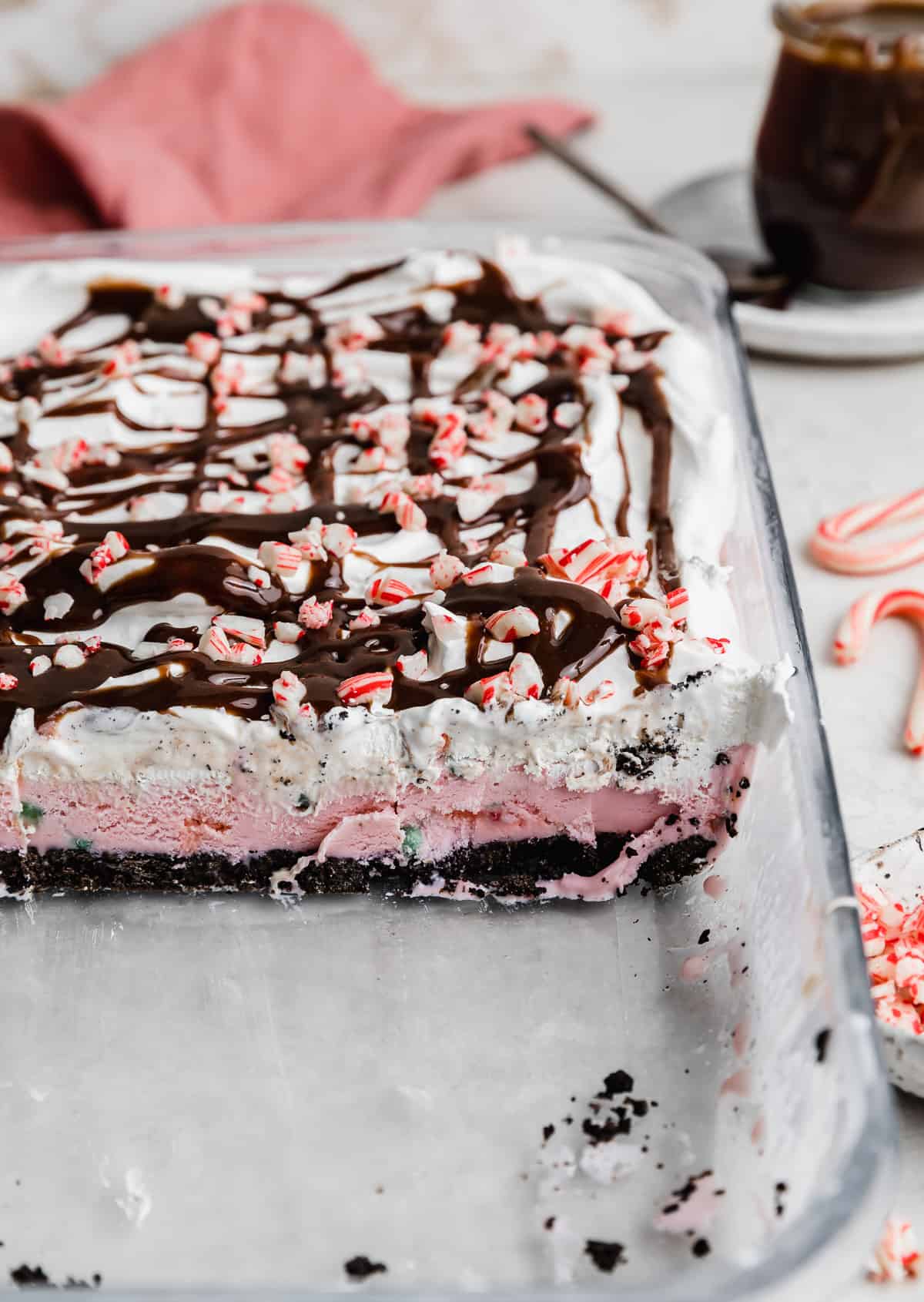 Christmas Ice Cream Cake cut into showing the Oreo crust, peppermint ice cream, whipped topping, and crushed candy cane layers. 