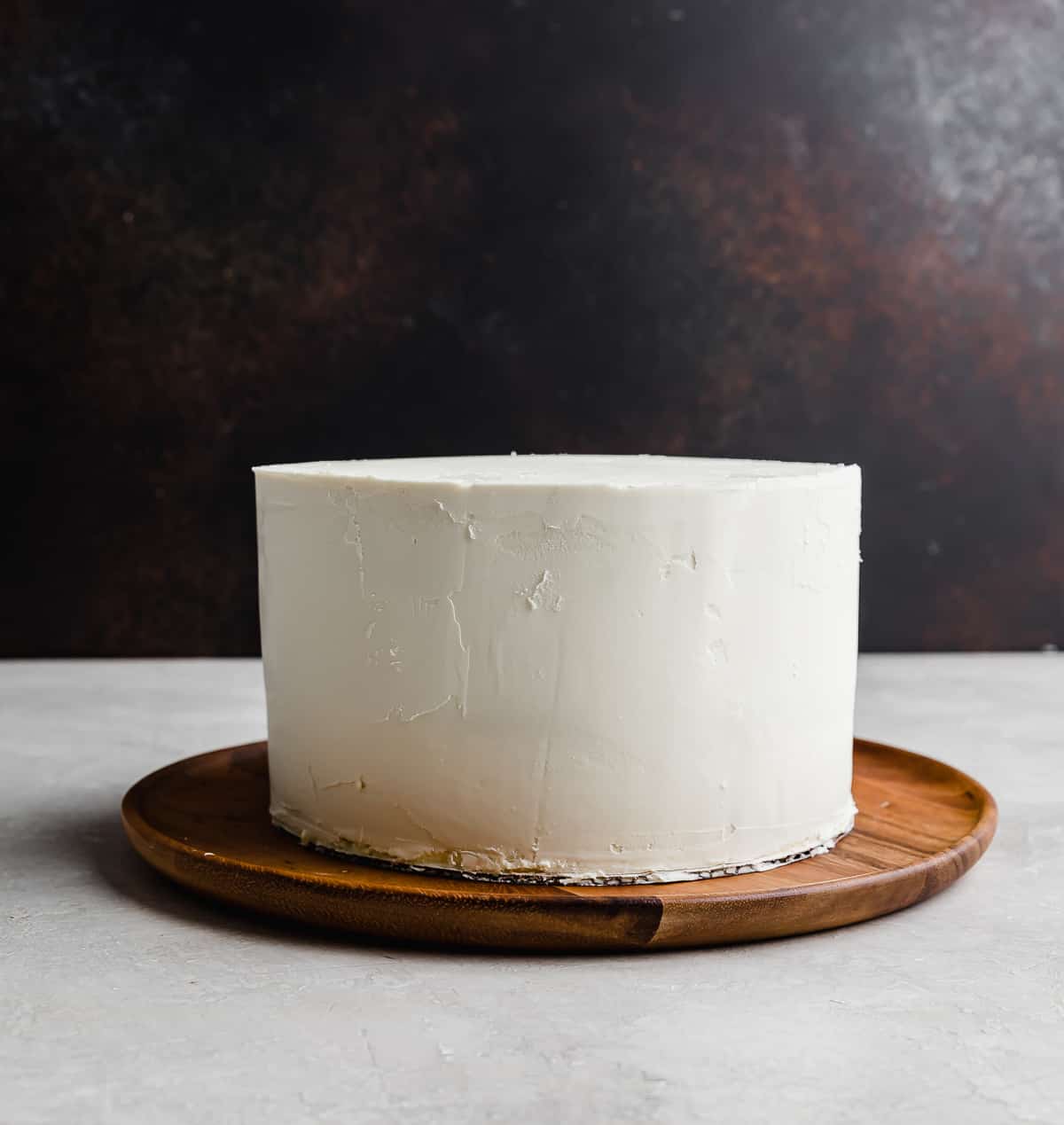 A white chocolate ganache covered round 3 tier layer cake.