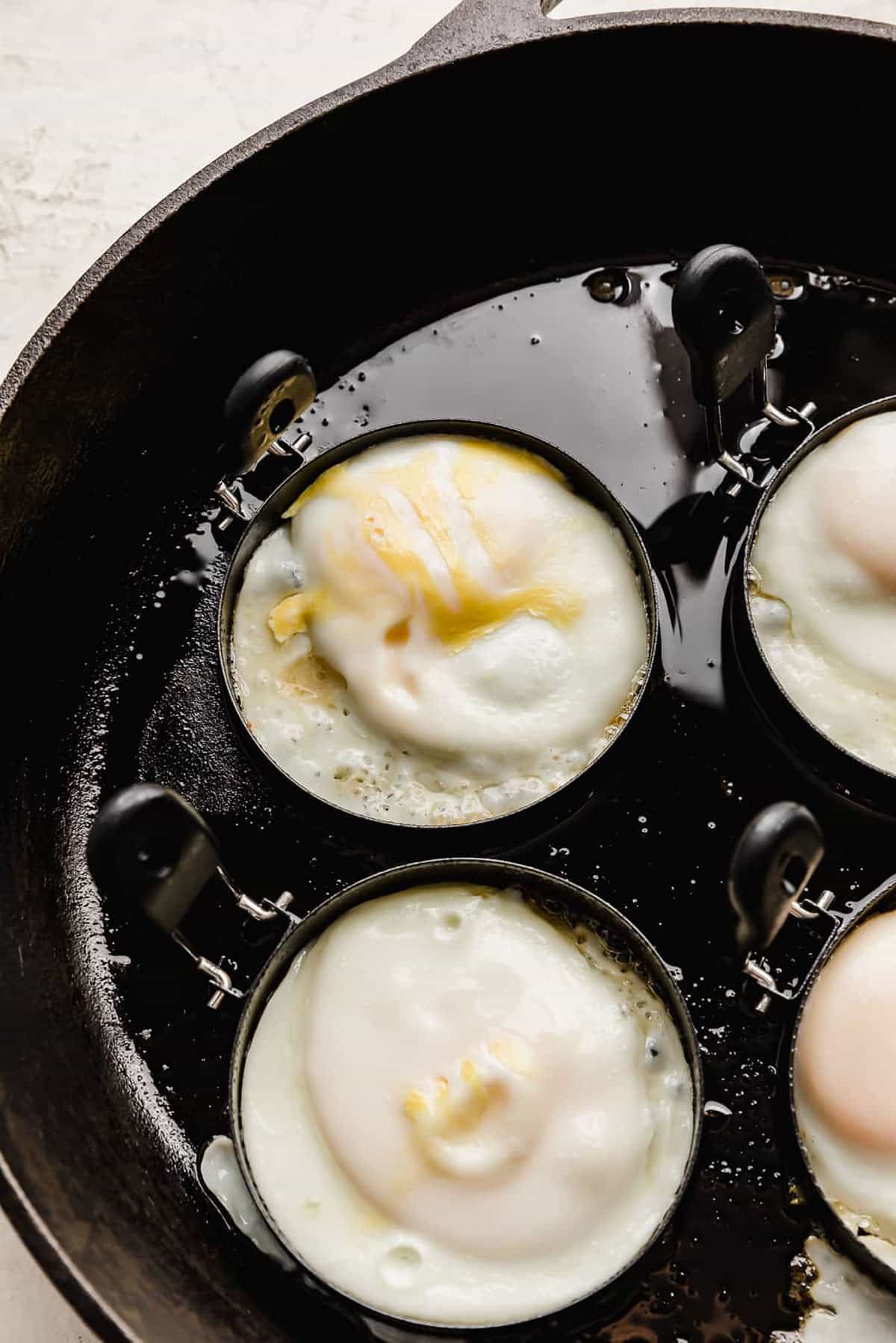 An egg in an egg ring in a black skillet.