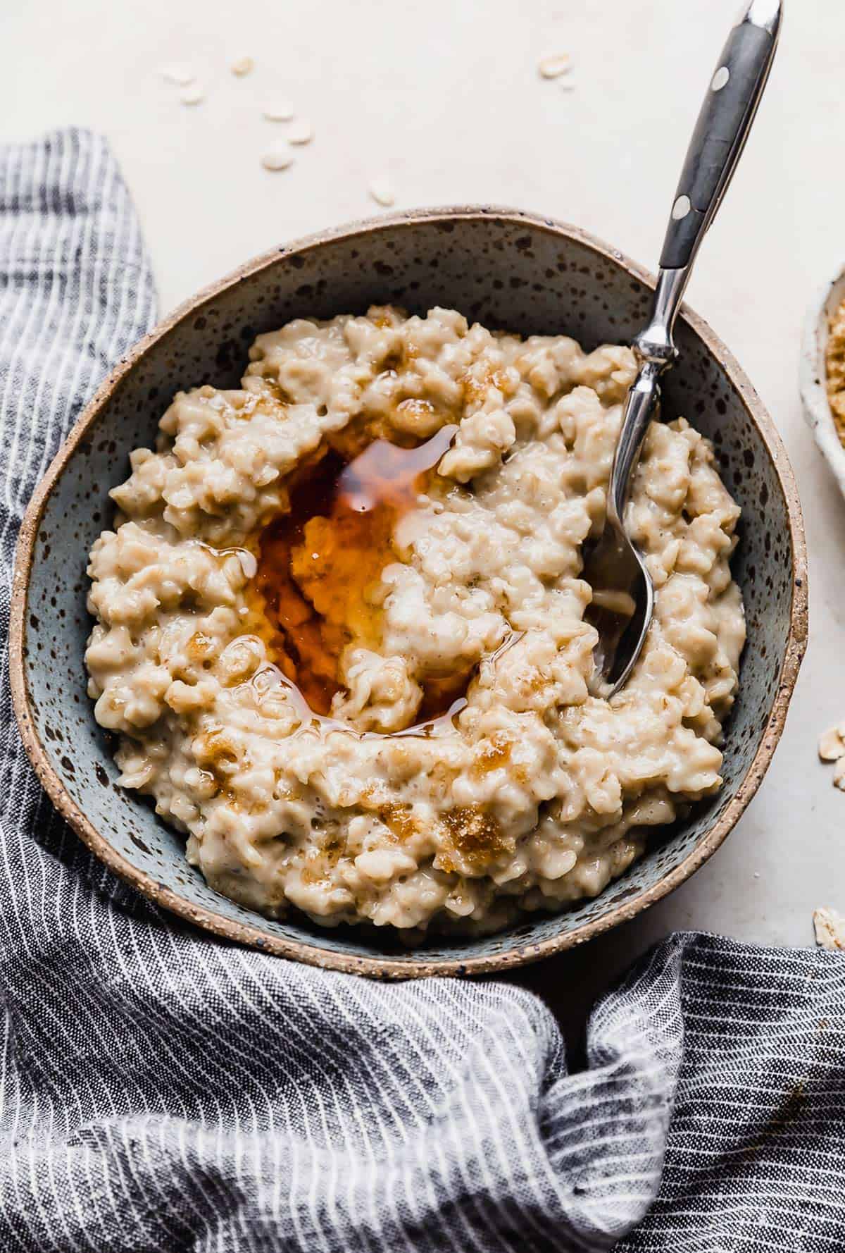 Maple and Brown Sugar Oatmeal in a blue bowl with a drizzle of maple syrup over the oatmeal.