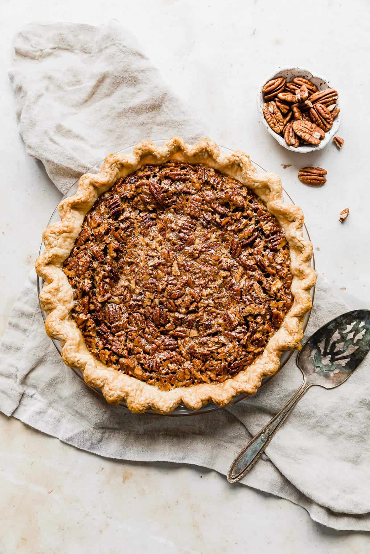 A baked Southern Pecan Pie on a tan colored linen. 