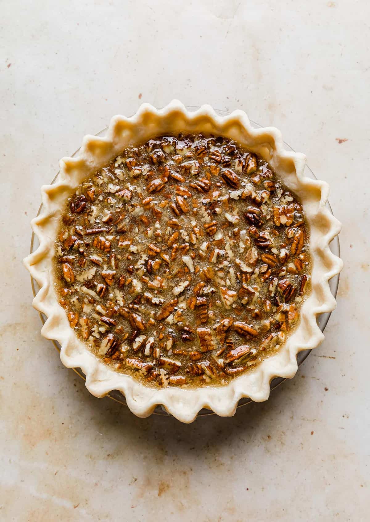 An unbaked southern pecan pie on a cream colored background.