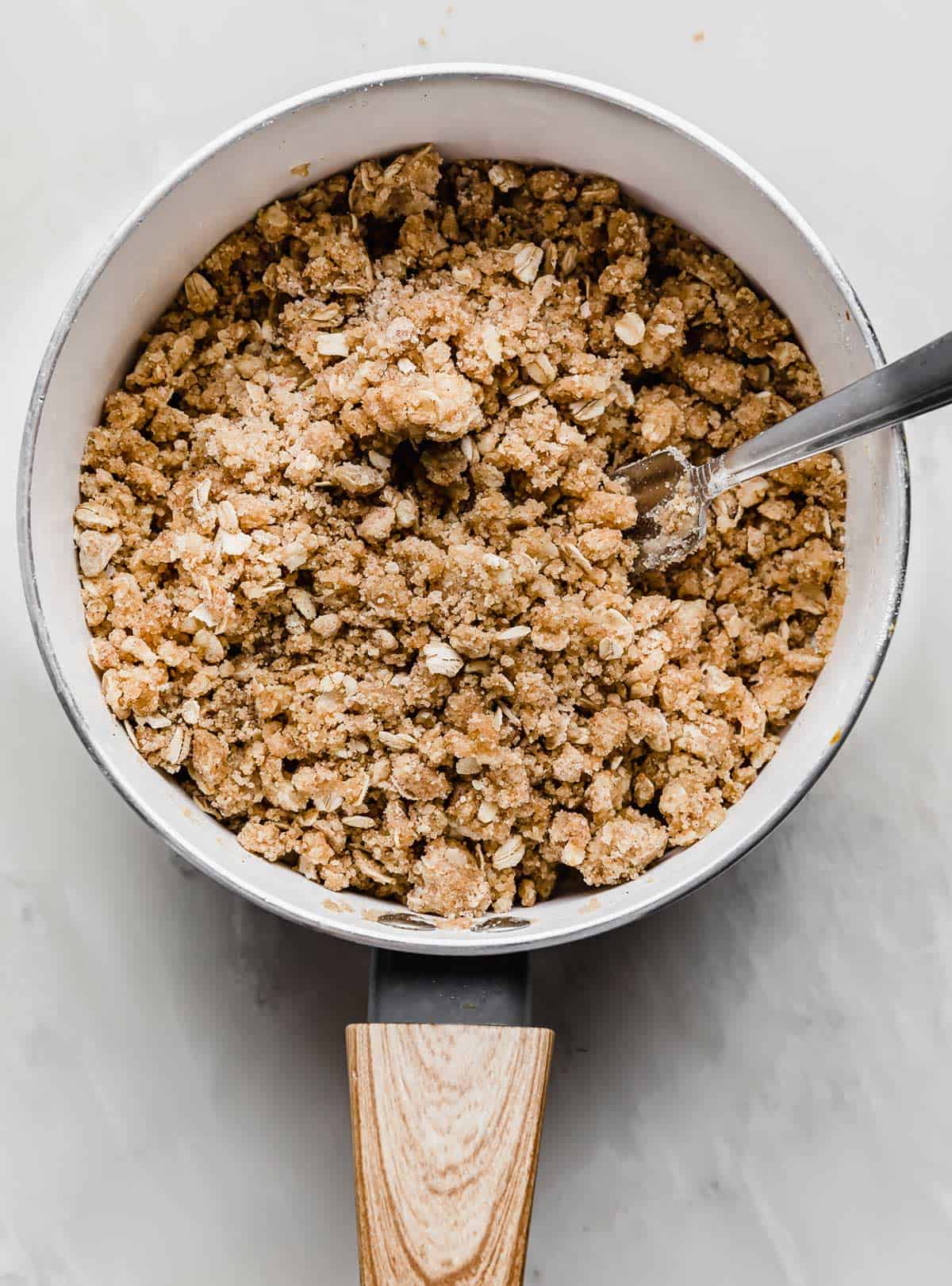 A fork stirring Streusel Topping with oats in a saucepan.
